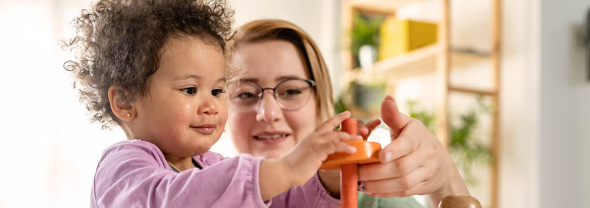 Mother looking at a child playing with an educational toy