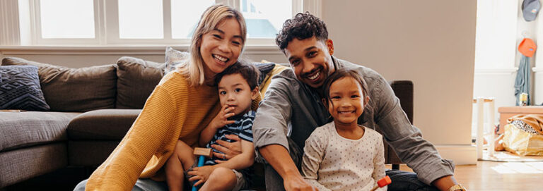 Young family smiling happily in their living room at home