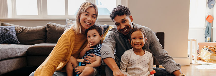 Young family smiling happily in their living room at home