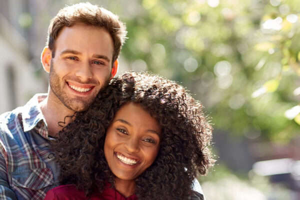 Diverse couple affectionately standing together outside on a sunny day