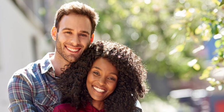Diverse couple affectionately standing together outside on a sunny day