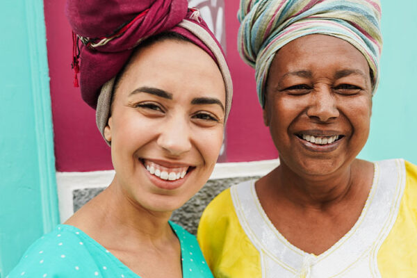 mother and her daughter wearing afro clothes with a colorful house in background