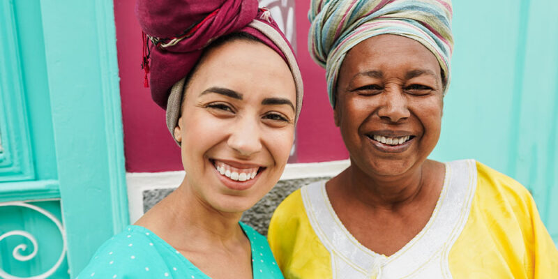 mother and her daughter wearing afro clothes with a colorful house in background