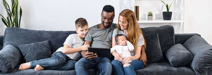 A multiracial family relaxing with a digital tablet sitting on the comfortable sofa