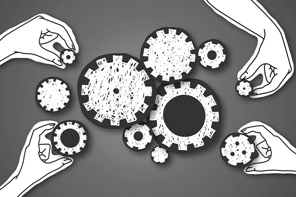 Paper hands connecting gears to each other over grey background